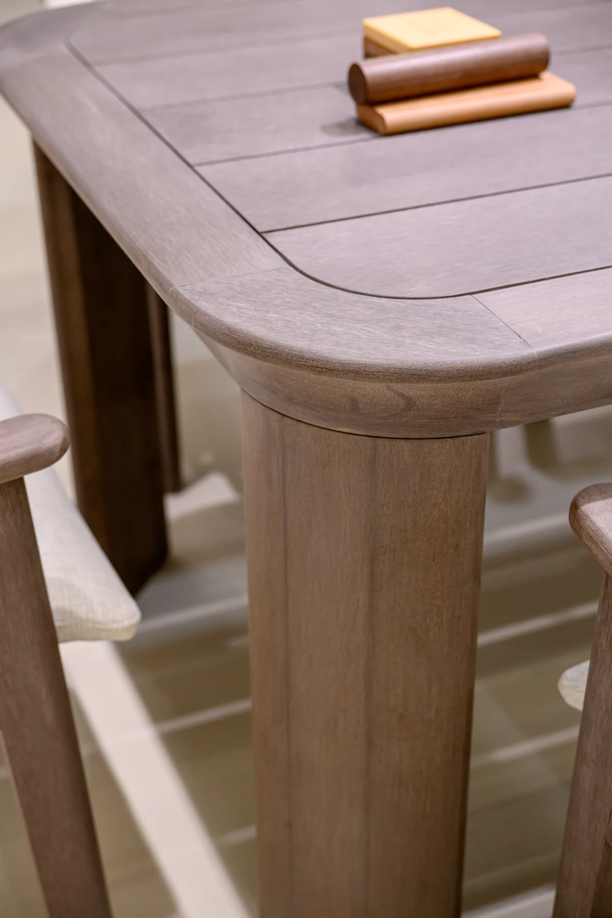 Corner and broad leg of an exhibited dining table with material samples on the top