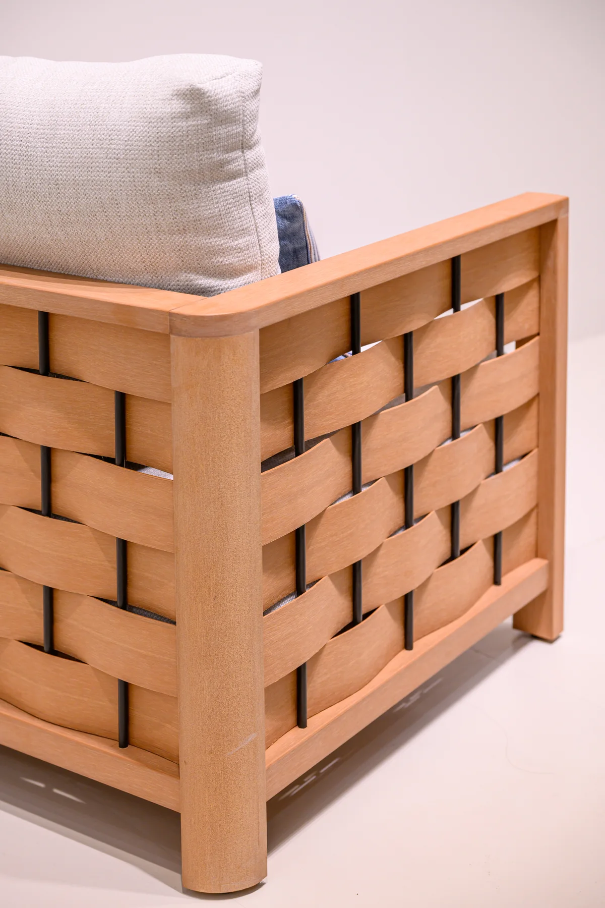 Back of an upholstered exhibition chair with a woven frame and separate cushions