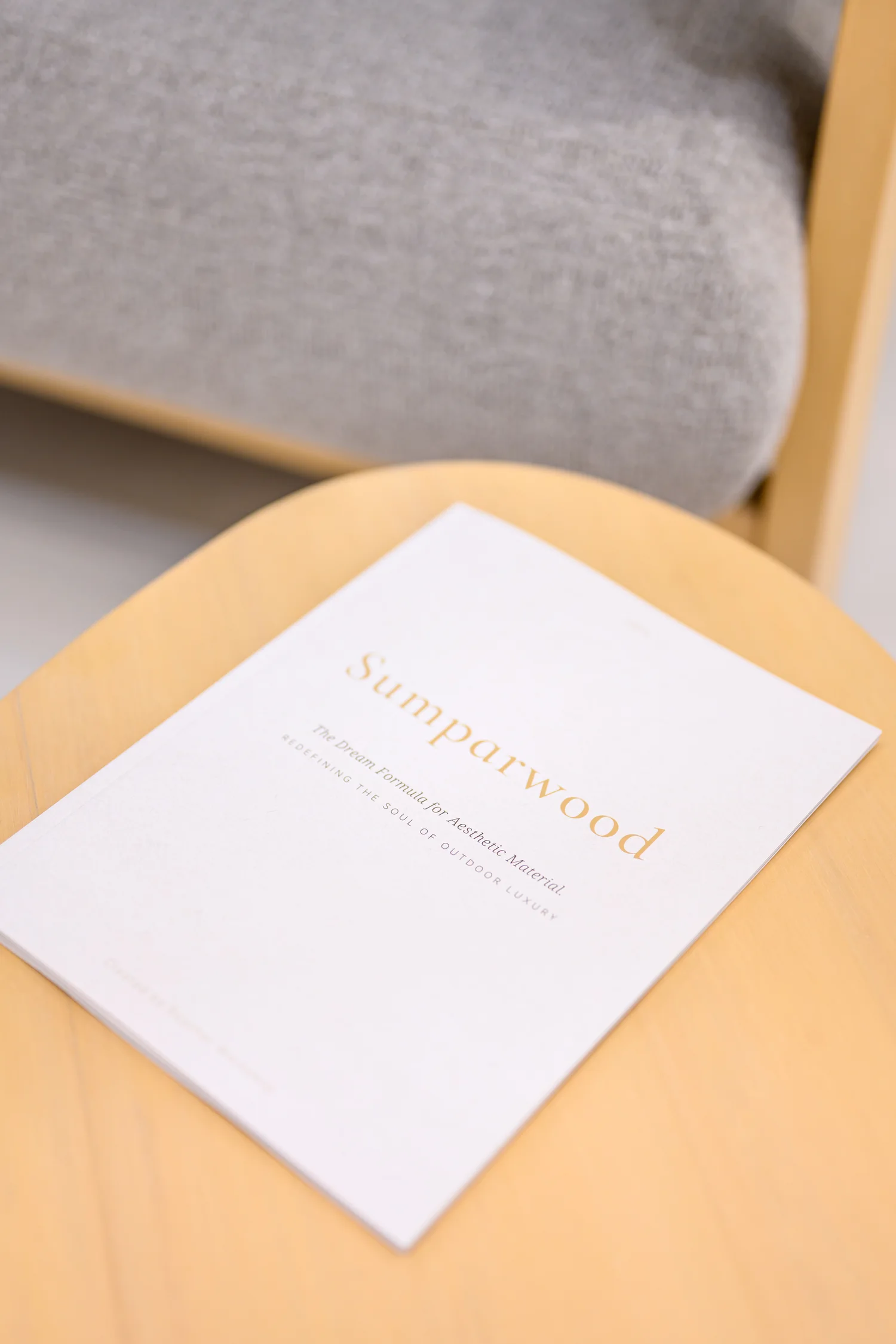 Closed Sumparwood Lookbook on a pale table beside an upholstered seat