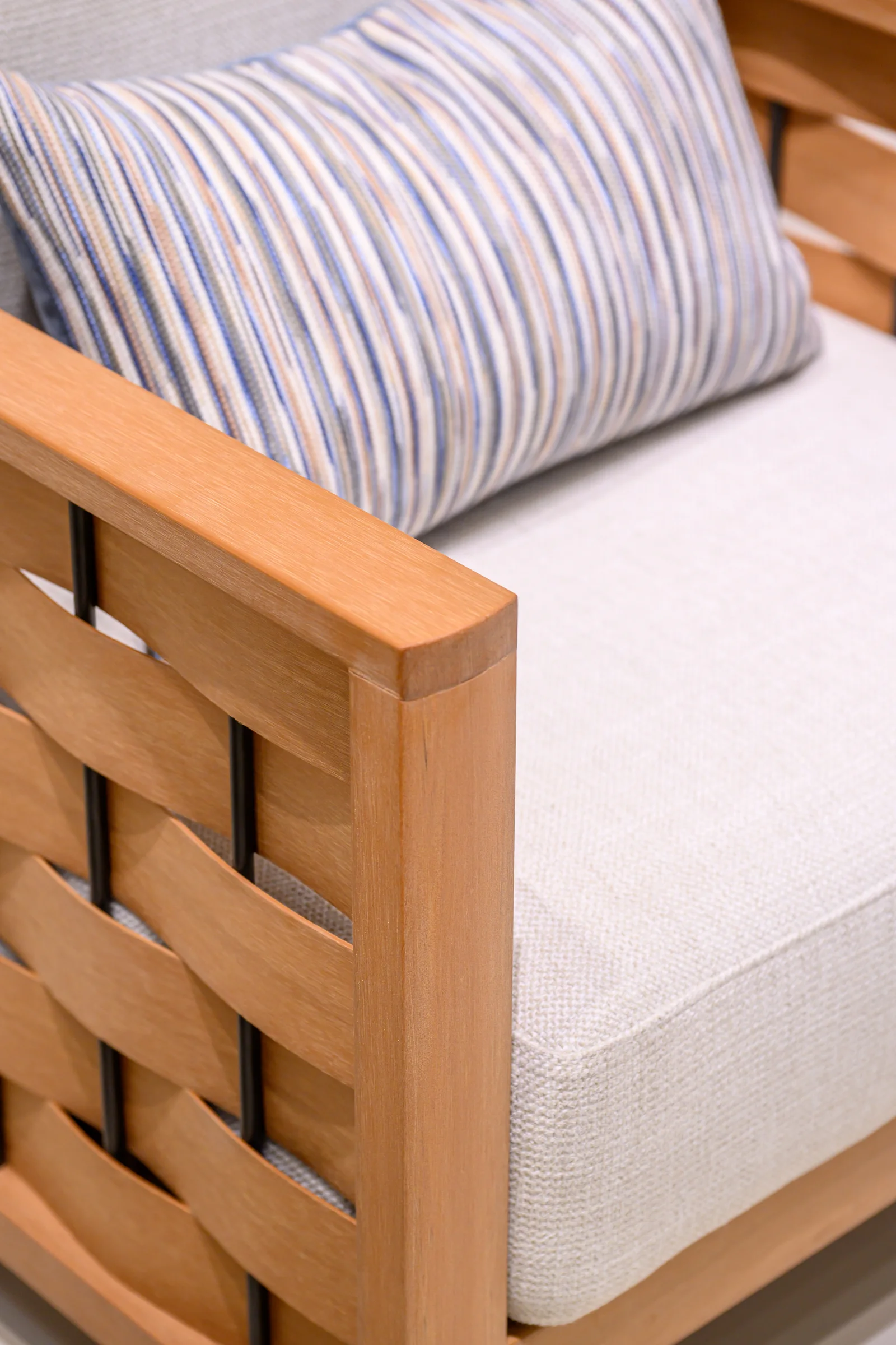Striped pillow behind a pale seat cushion and broad interlaced chair-frame members
