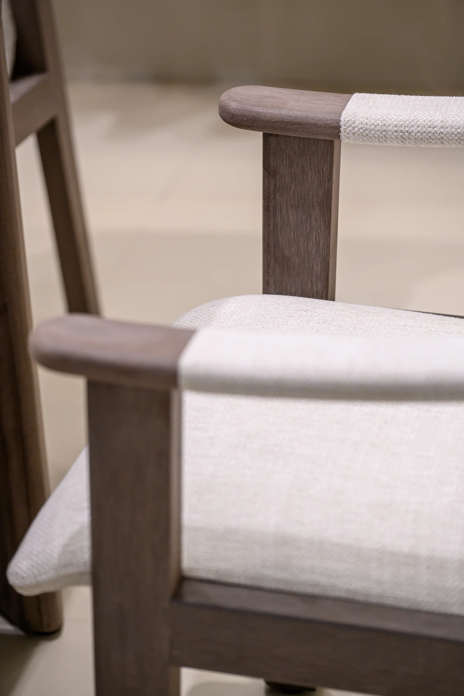 Pale upholstery meeting the dark arm and back frame of an exhibition chair