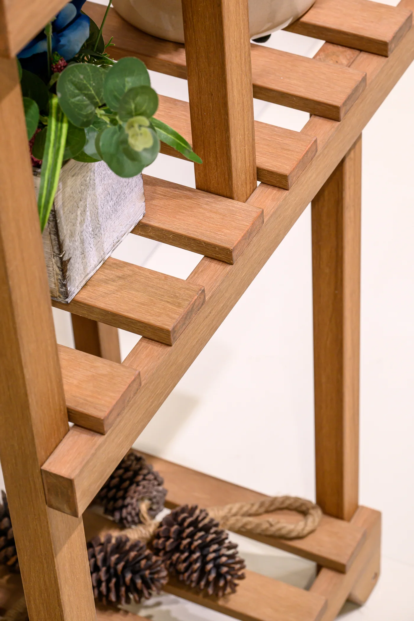 Slatted shelf meeting upright frame members beside display foliage