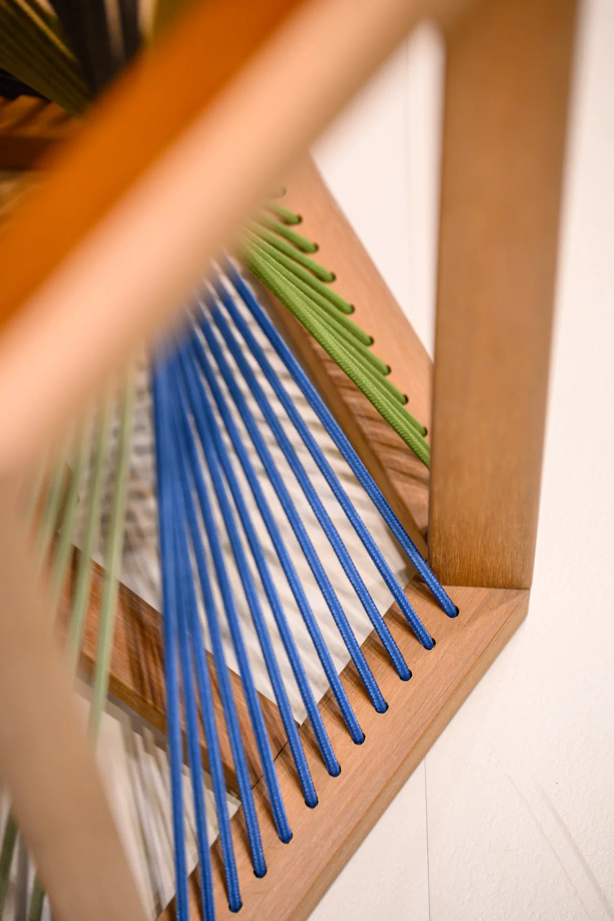 Blue and green cords passing through holes in a warm-toned furniture frame
