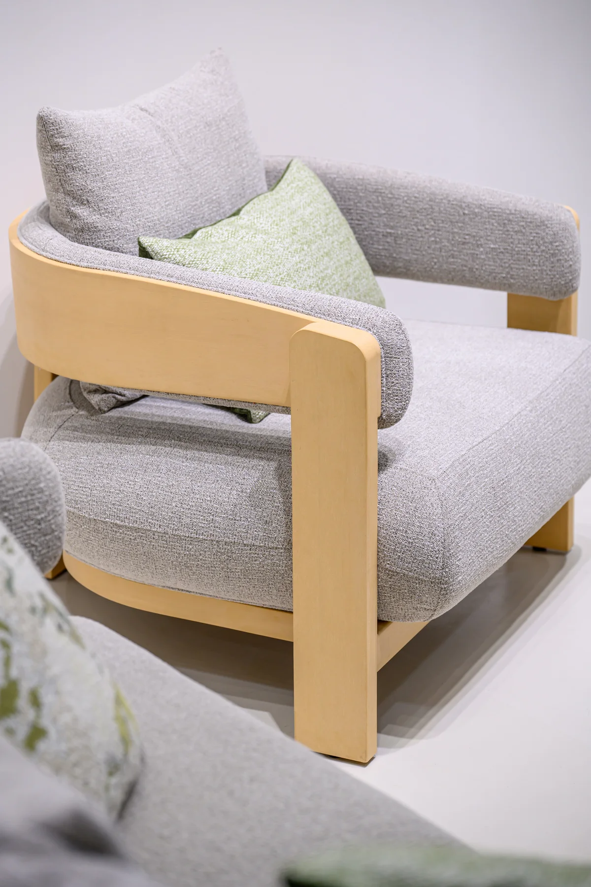 Pale curved armchair with upholstered inner back and rounded front uprights