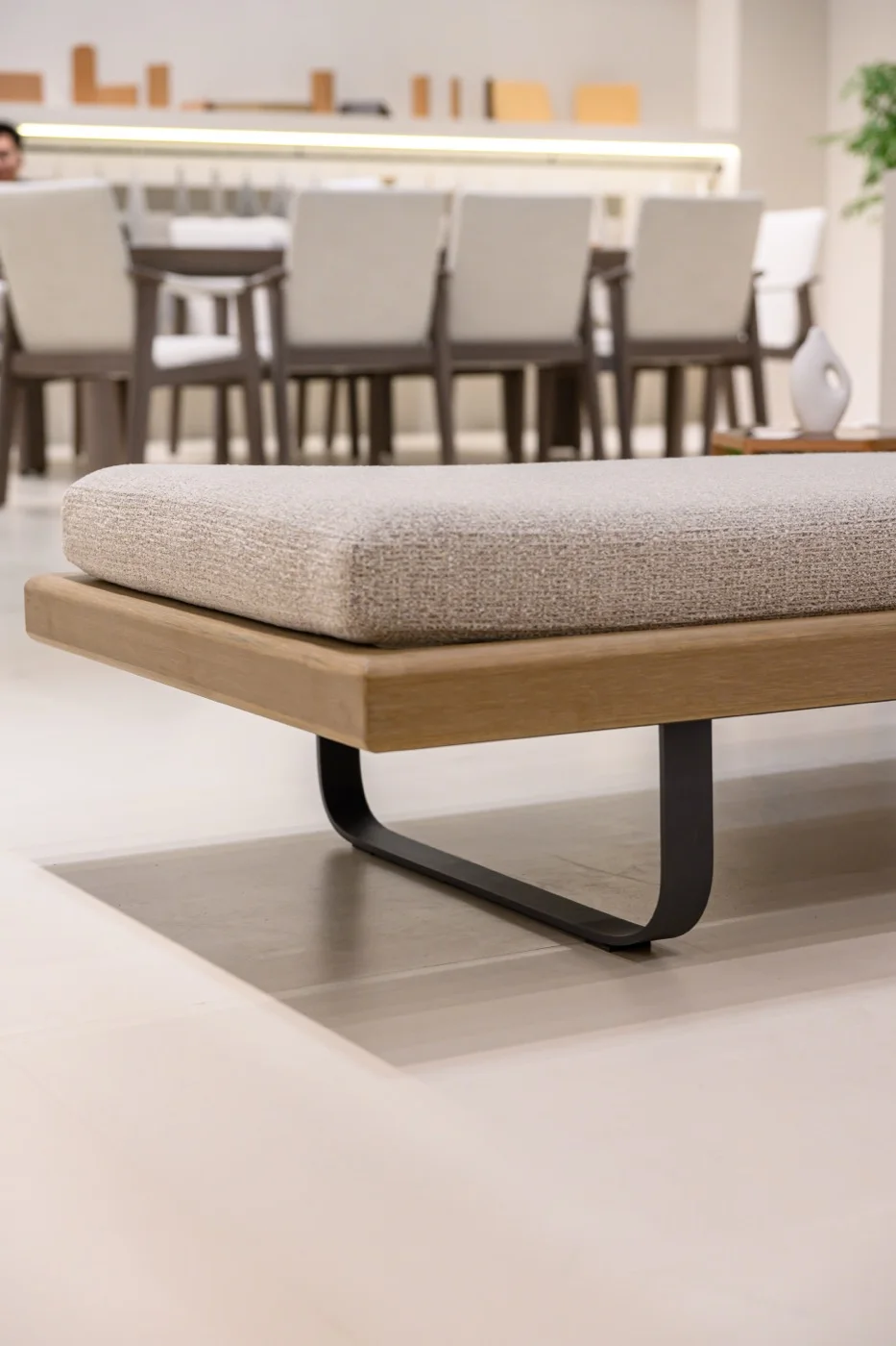 Upholstered lounger platform above a dark curved support in an exhibition space