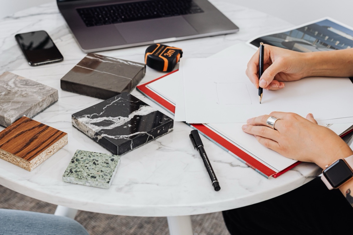 Designer reviewing drawings and material samples on a worktable.