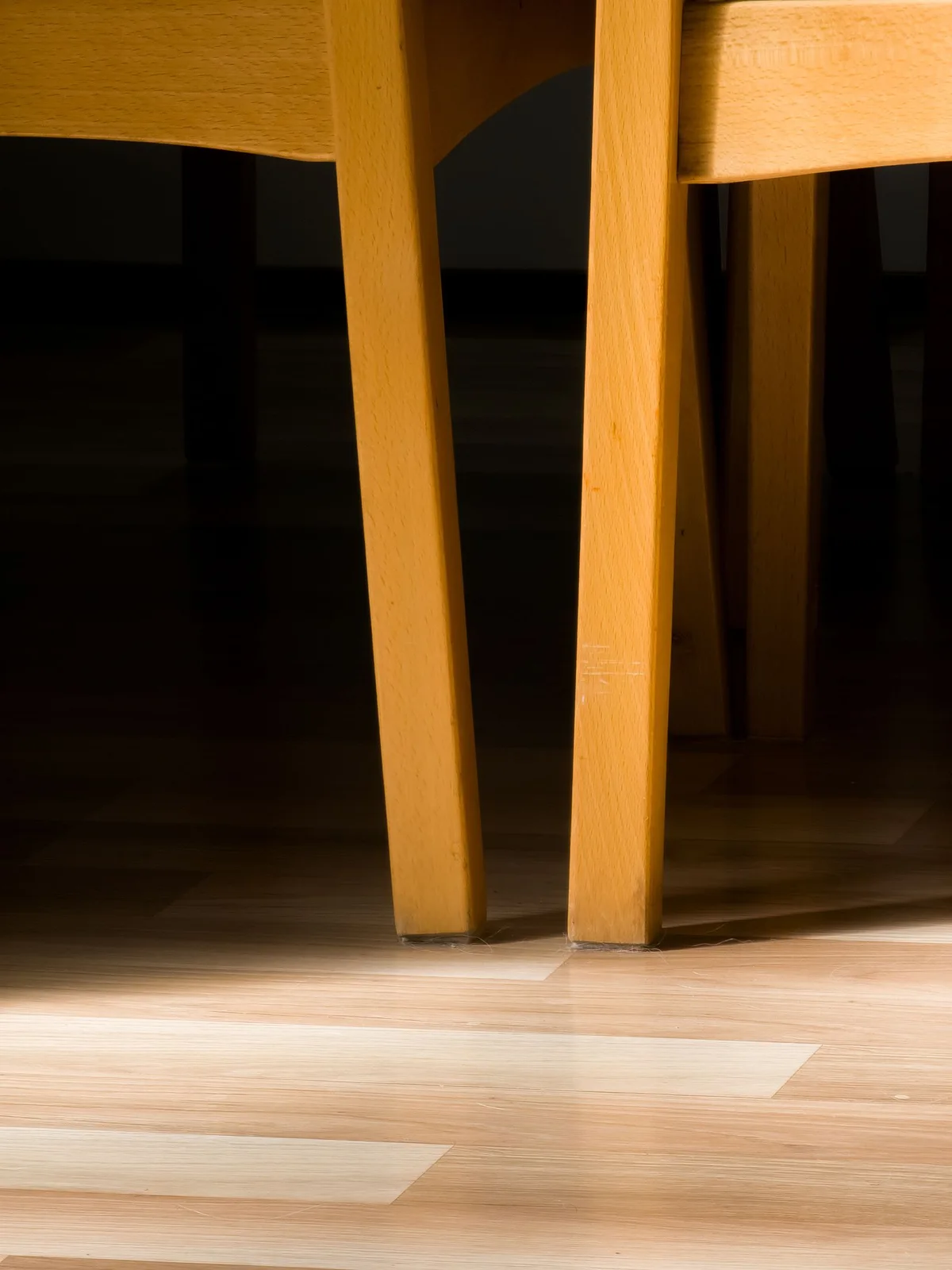 Wooden chair legs meeting a patterned indoor floor in sunlight