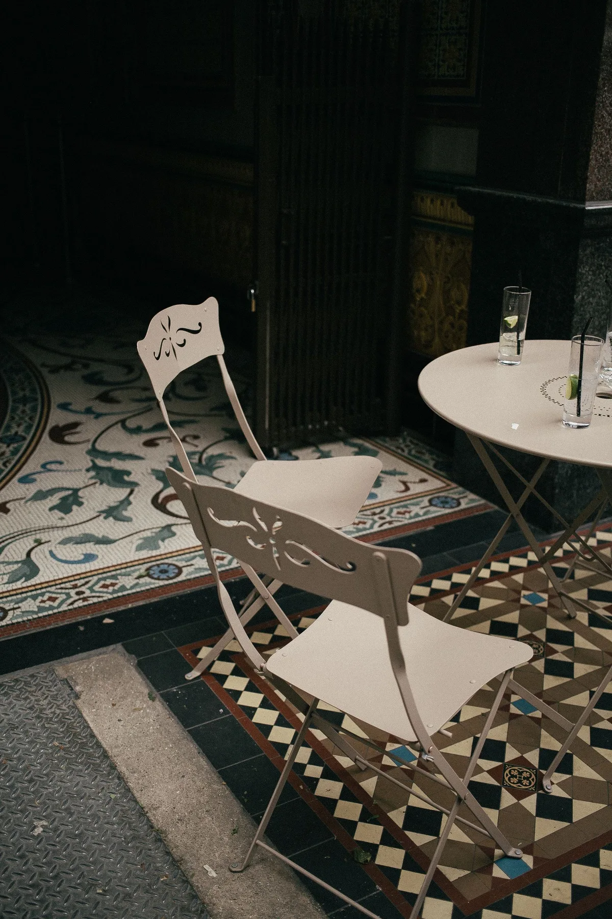 White folding chairs standing beside a change from patterned tile to pavement