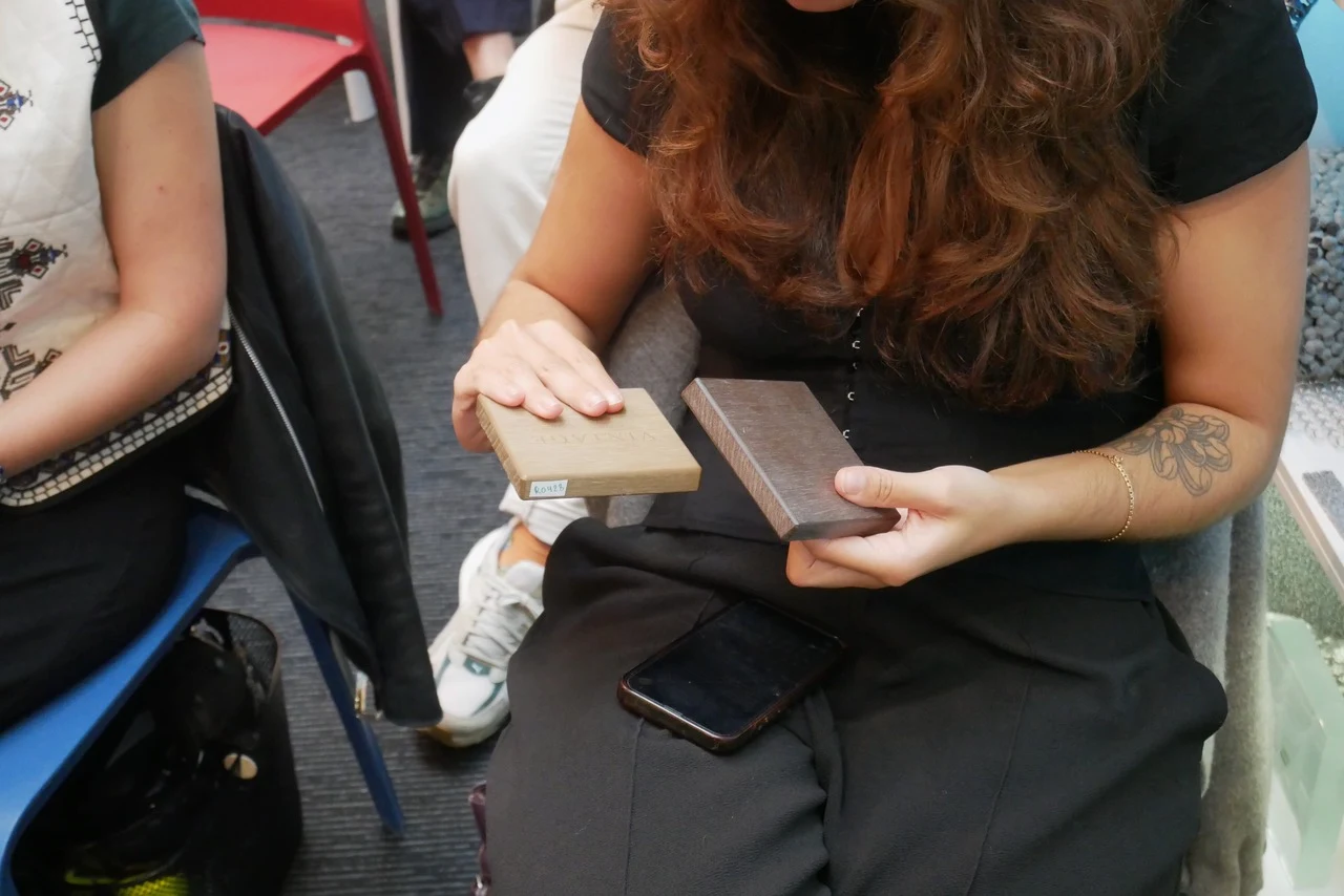 Attendee touching a light Sumparwood sample while holding a darker sample beside it