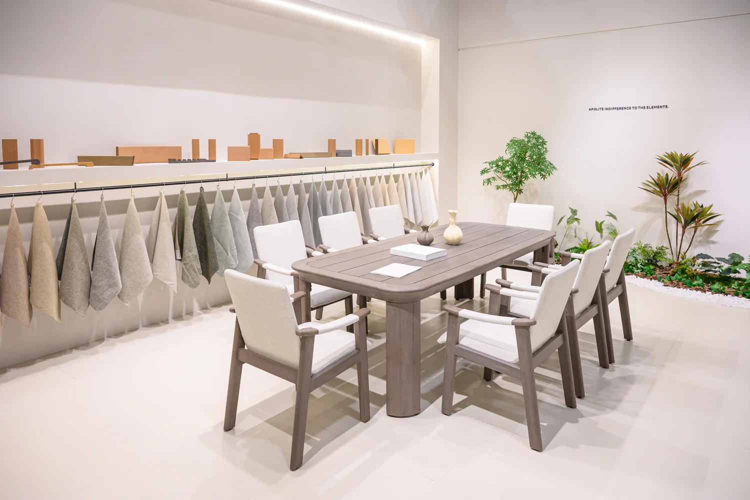 Hanging fabric swatches behind an upholstered dining table and chairs
