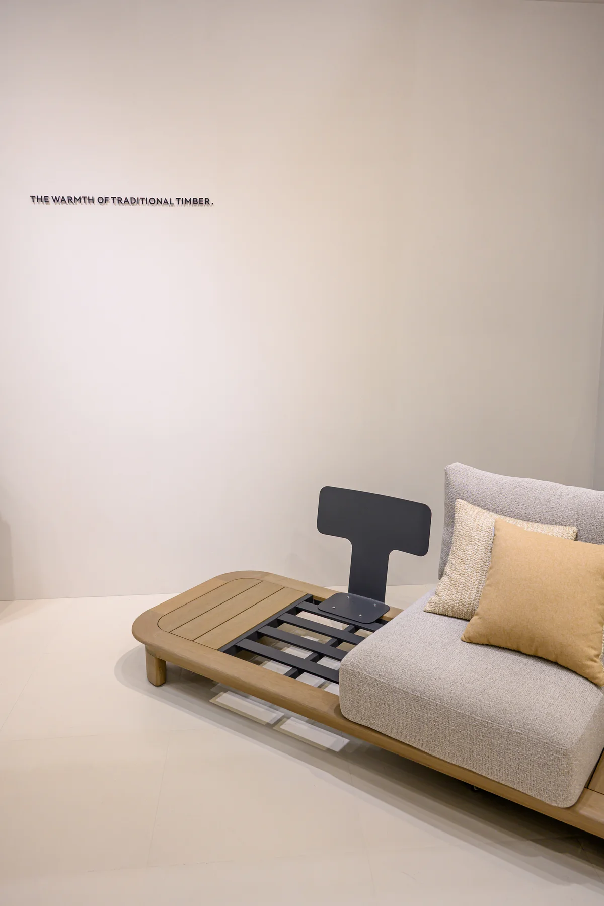 Exhibited sofa with separate pale cushions and an exposed platform at one end