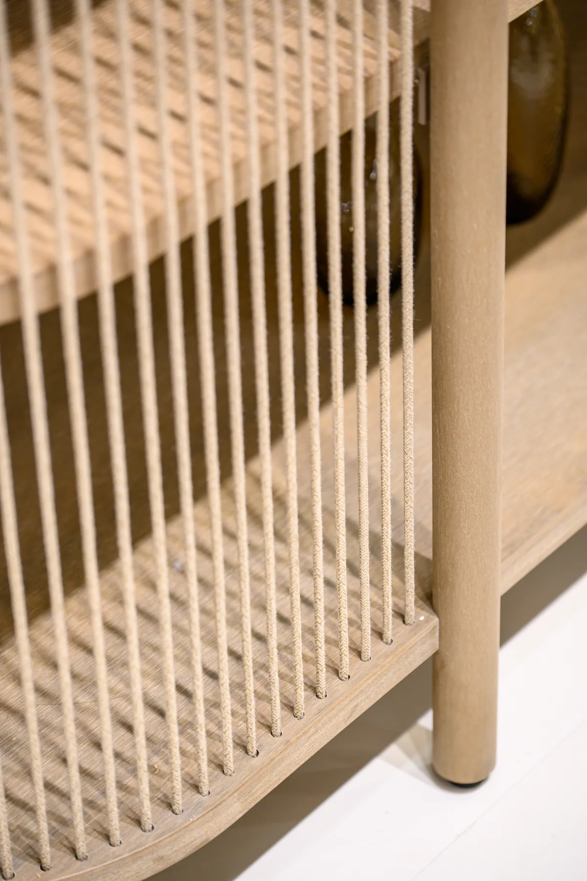 Vertical woven cords beside a warm-toned frame and rounded upright