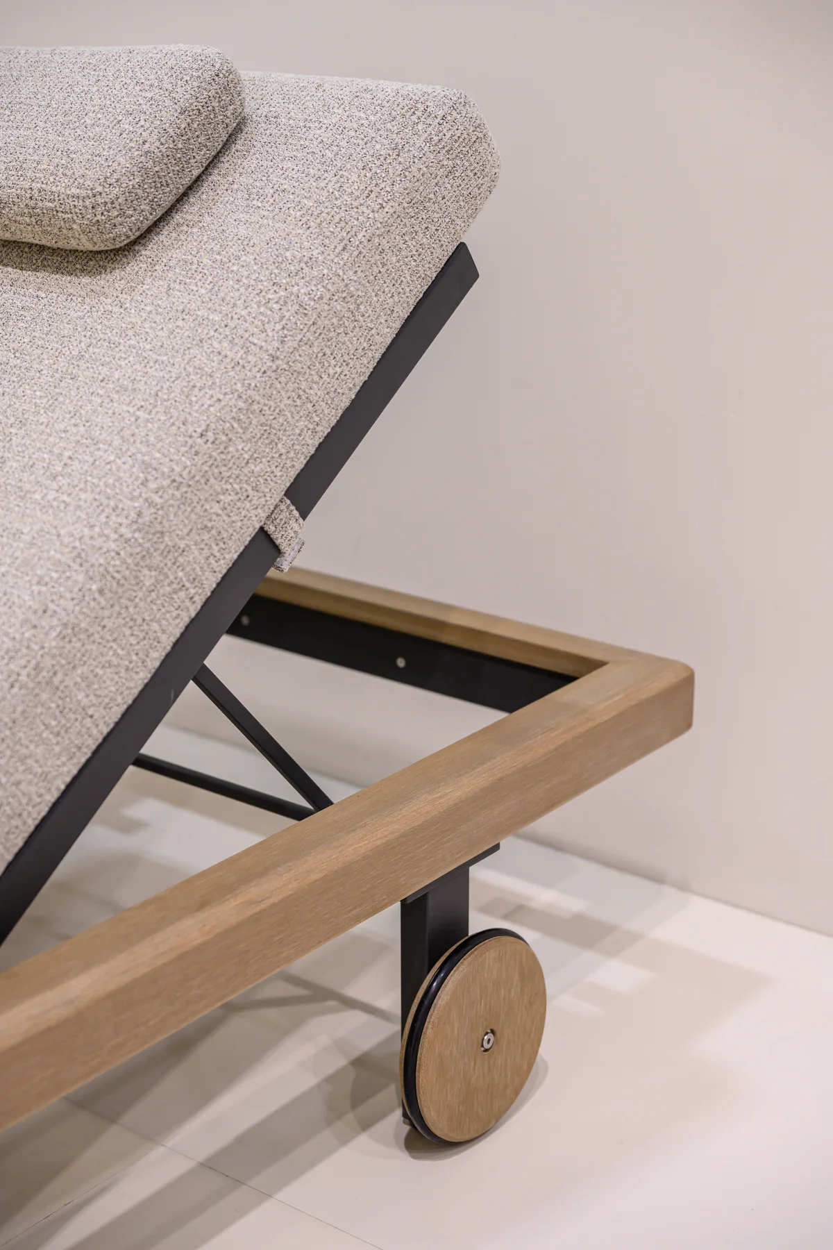 Raised upholstered lounger back above an open frame and wheel