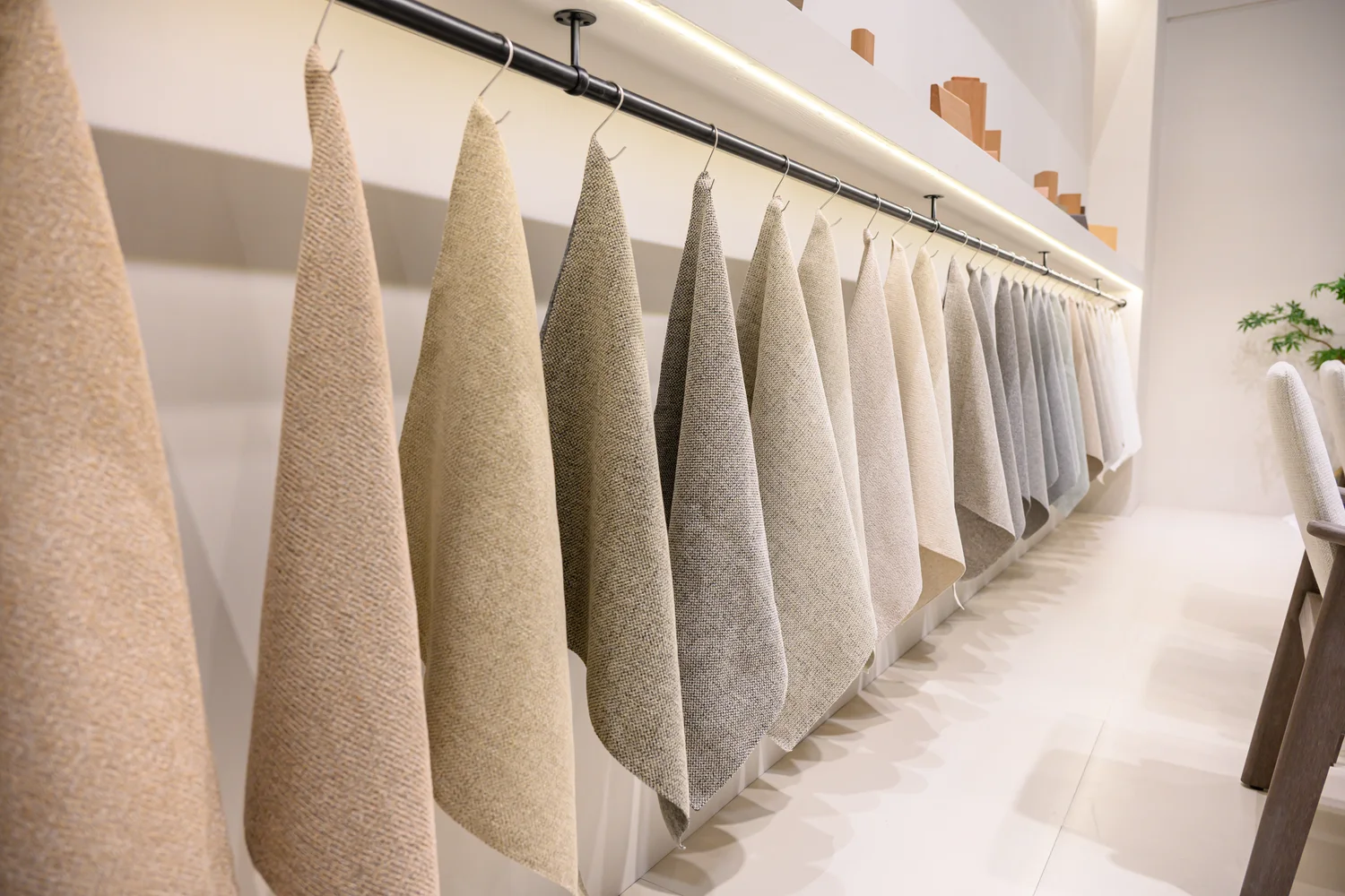 A row of differently coloured textile swatches hanging from a rail at an exhibition