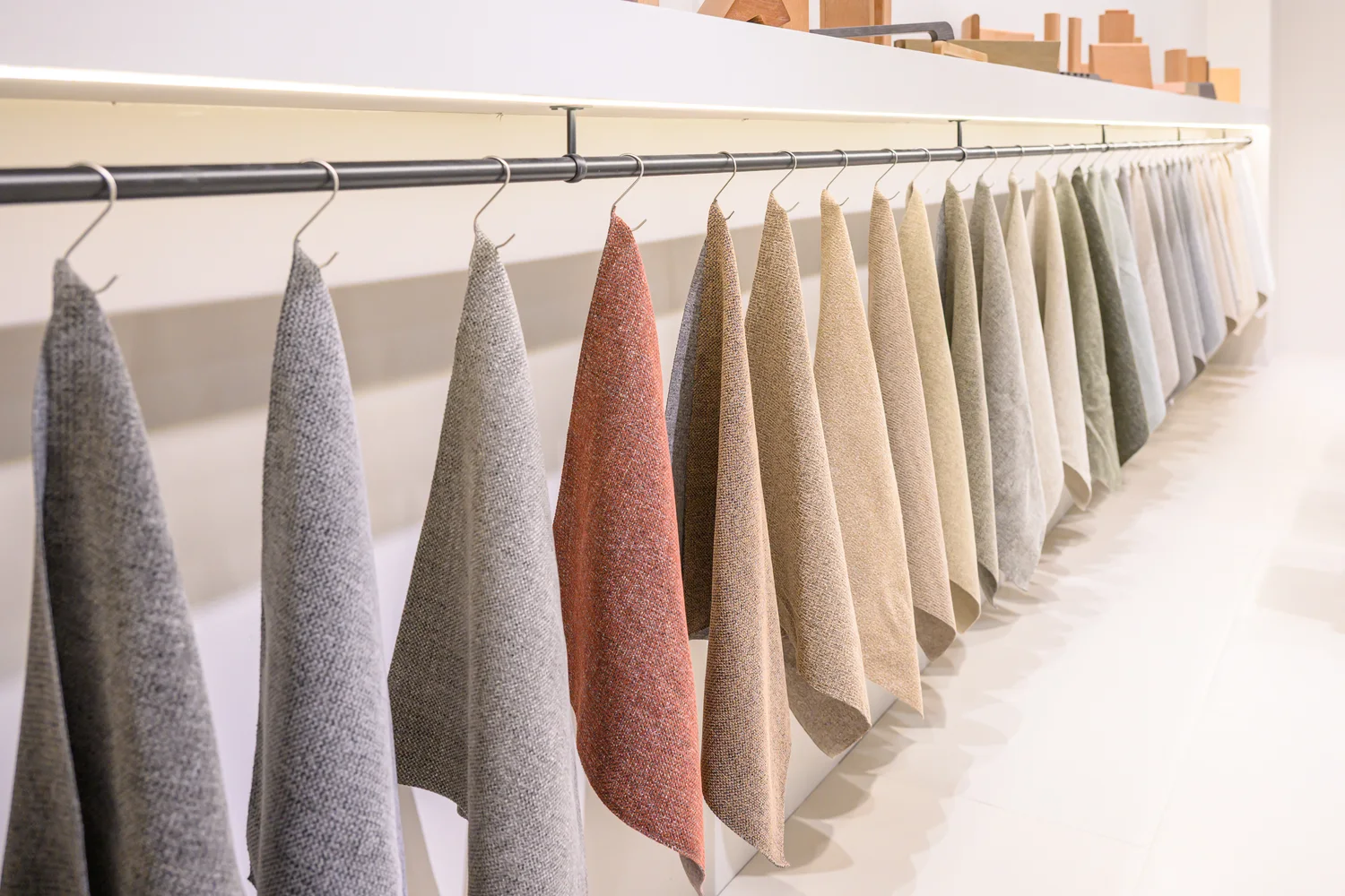 Hanging textile swatches in different colours on an exhibition rail