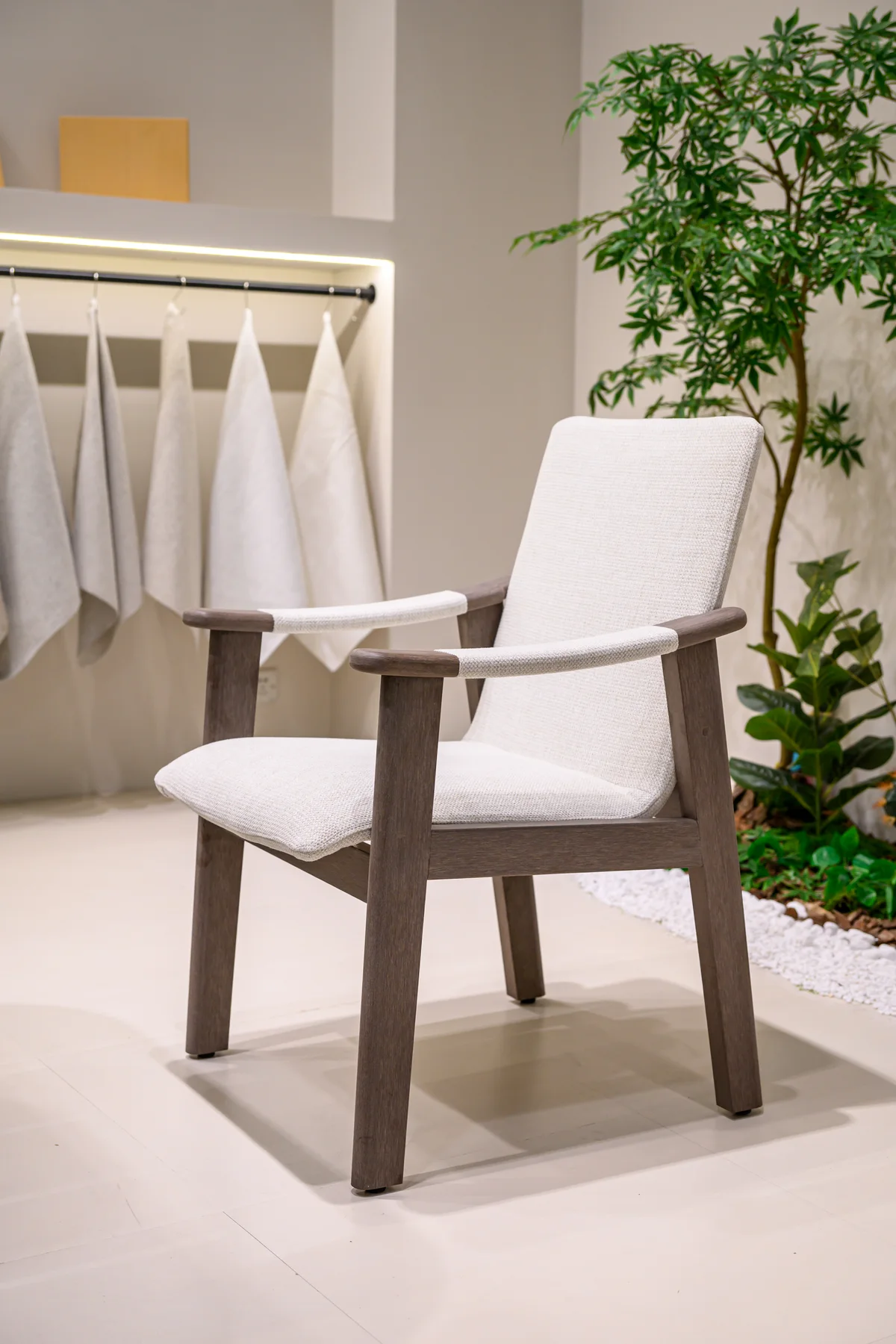 Full chair with broad arms and pale seat cushion in an exhibition setting