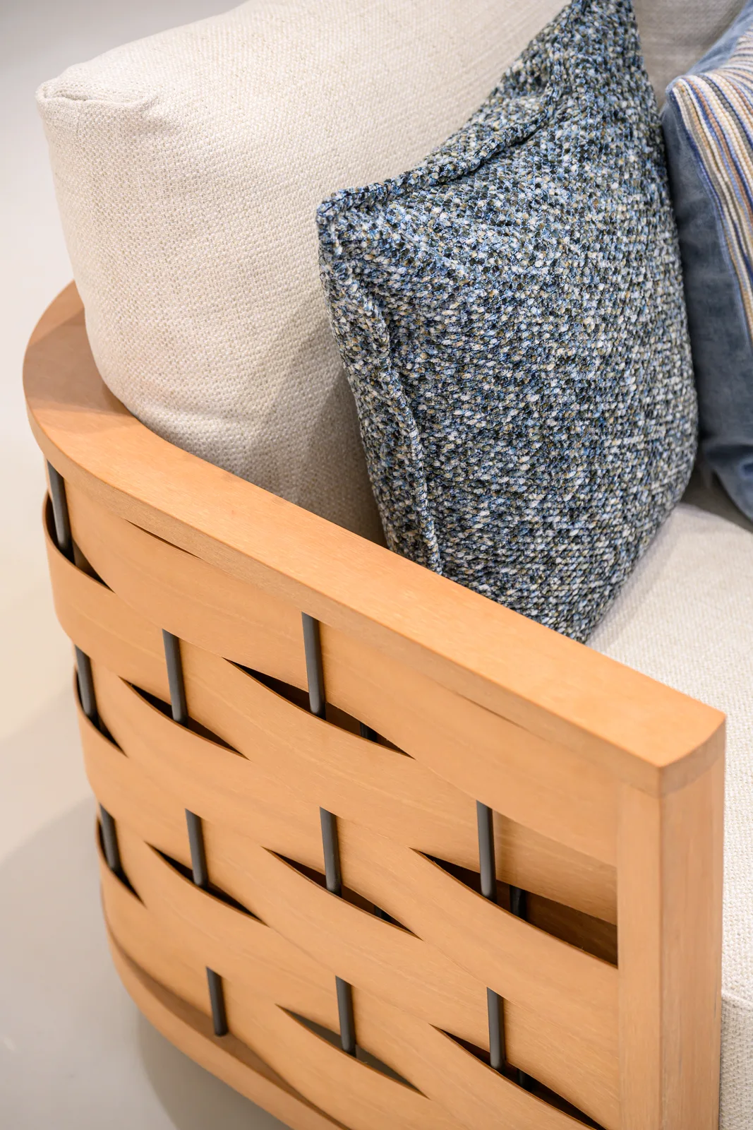 Pale back cushion and blue scatter cushions beside a woven-pattern furniture frame