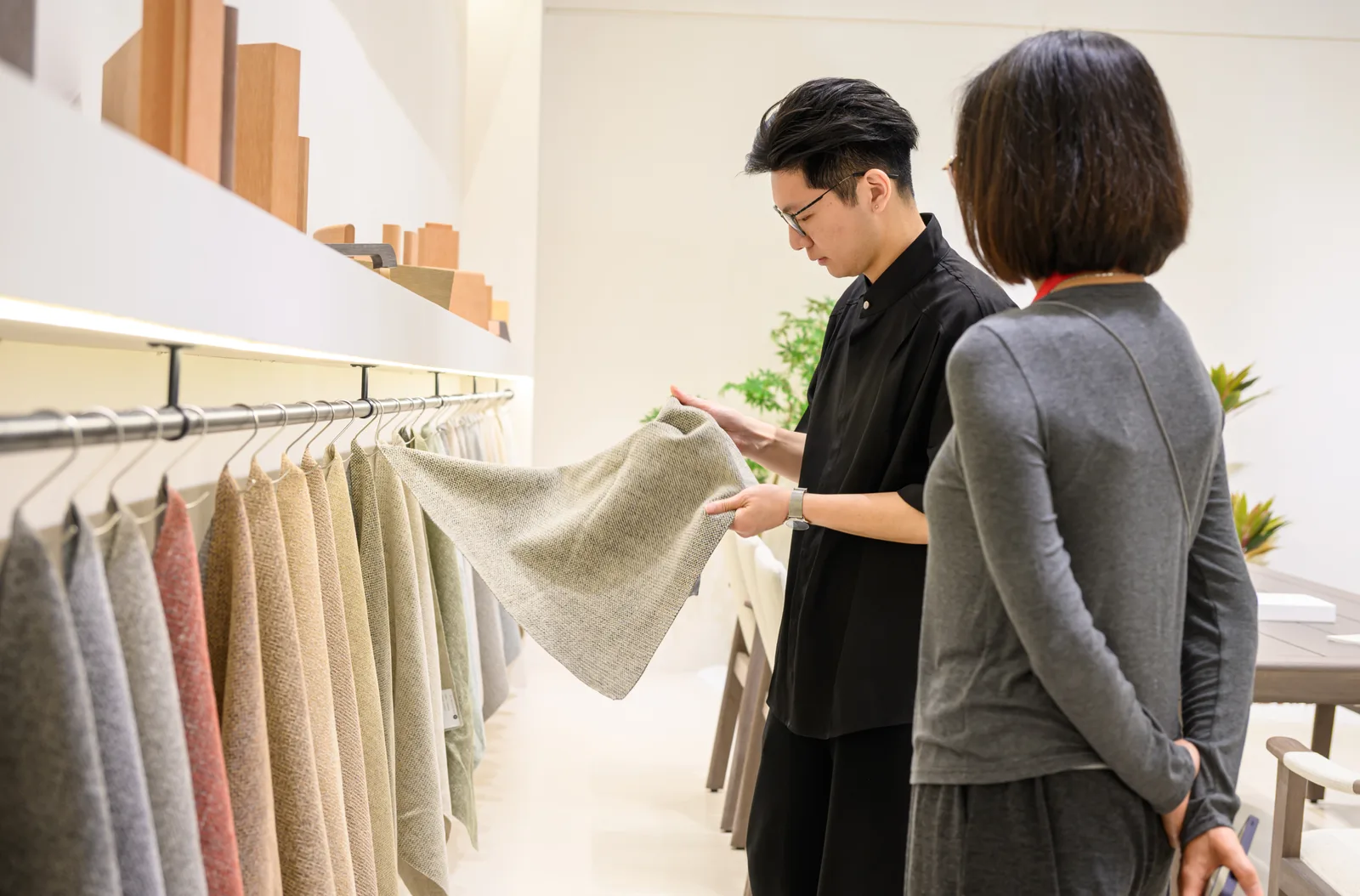 Two exhibition visitors examining a large neutral fabric swatch