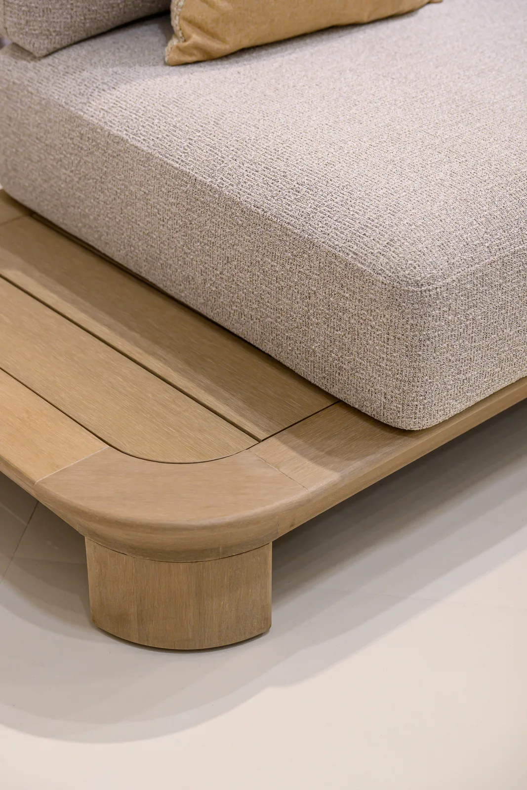 Rounded corner and seam of a pale seat cushion on a furniture platform