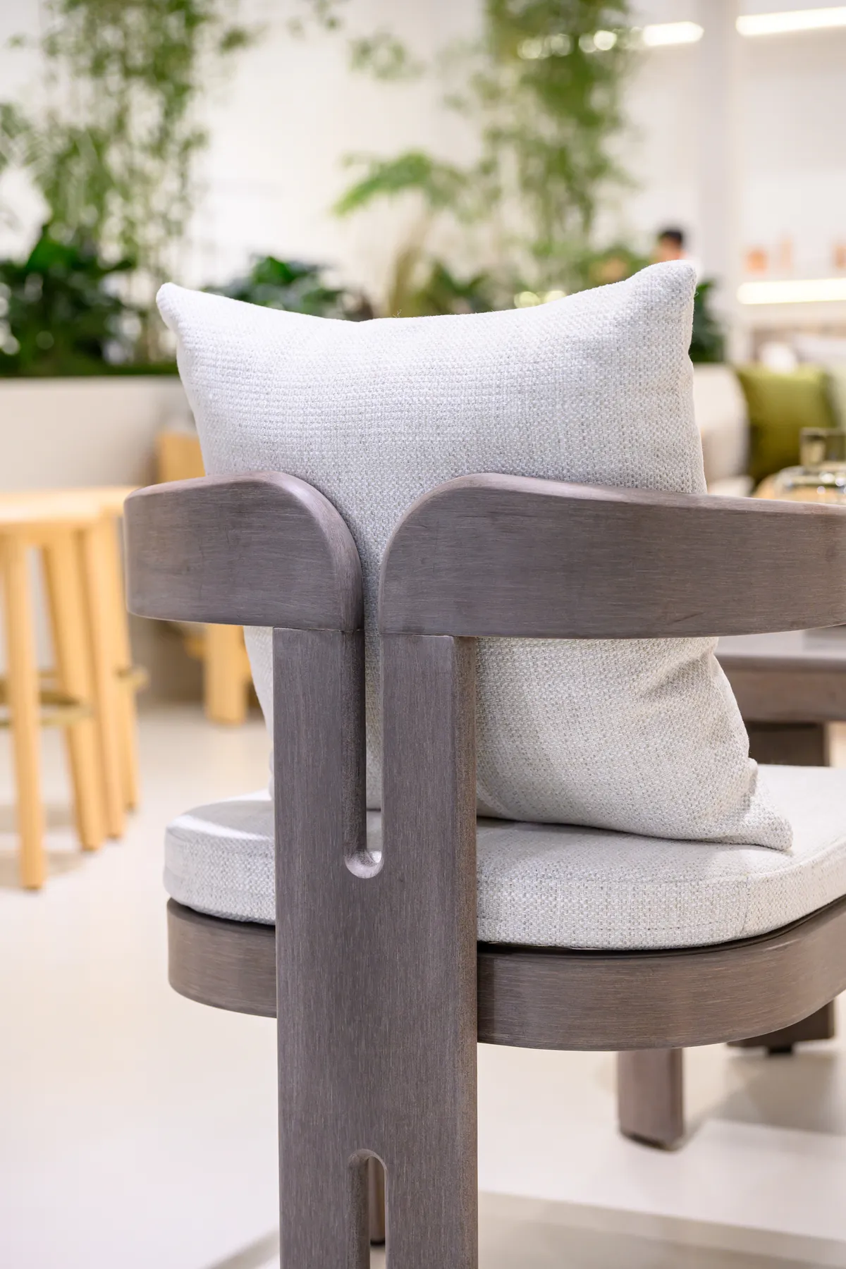Dark curved chair back with a central split detail and cream cushion