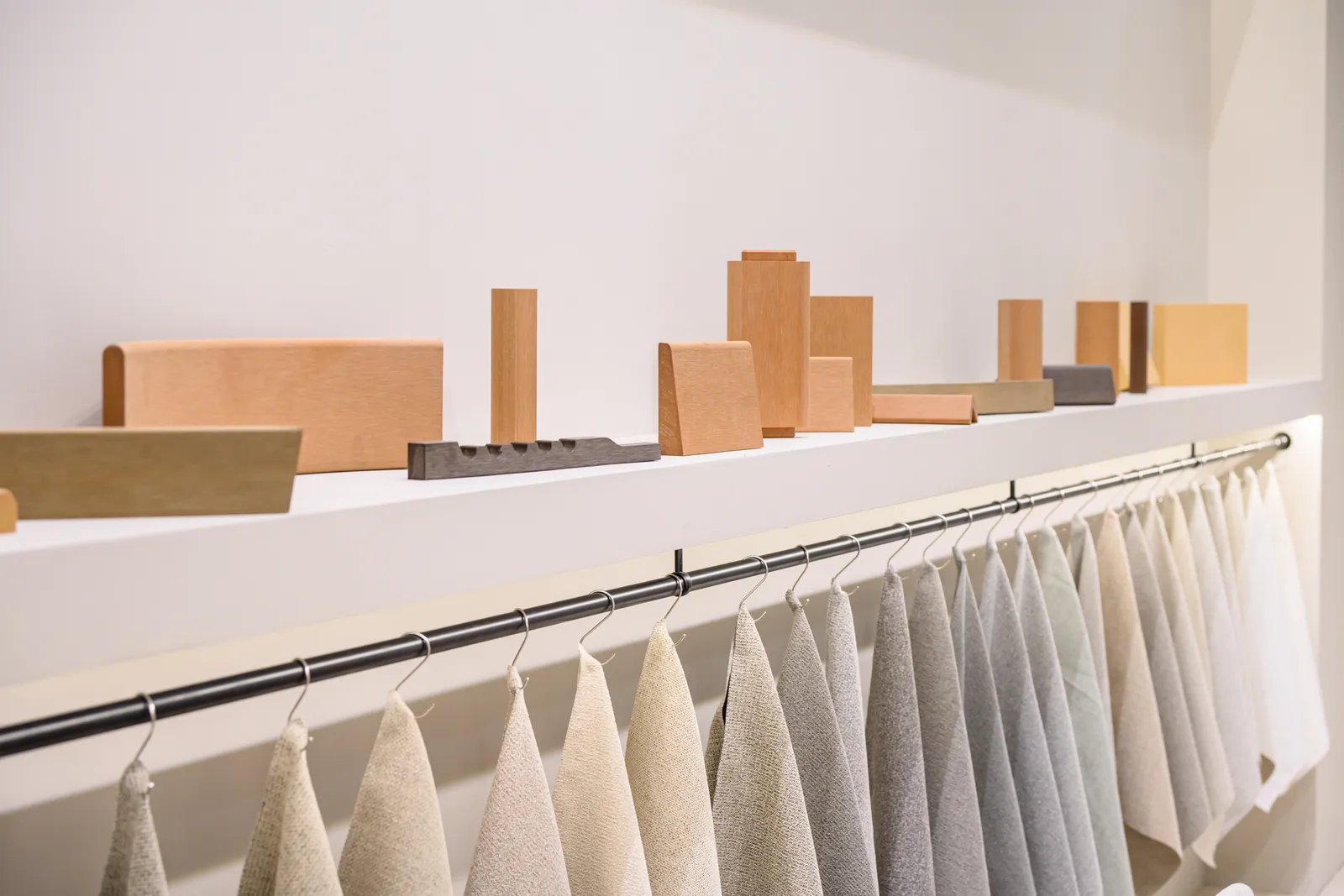 Material profiles displayed on a shelf above hanging neutral fabric swatches
