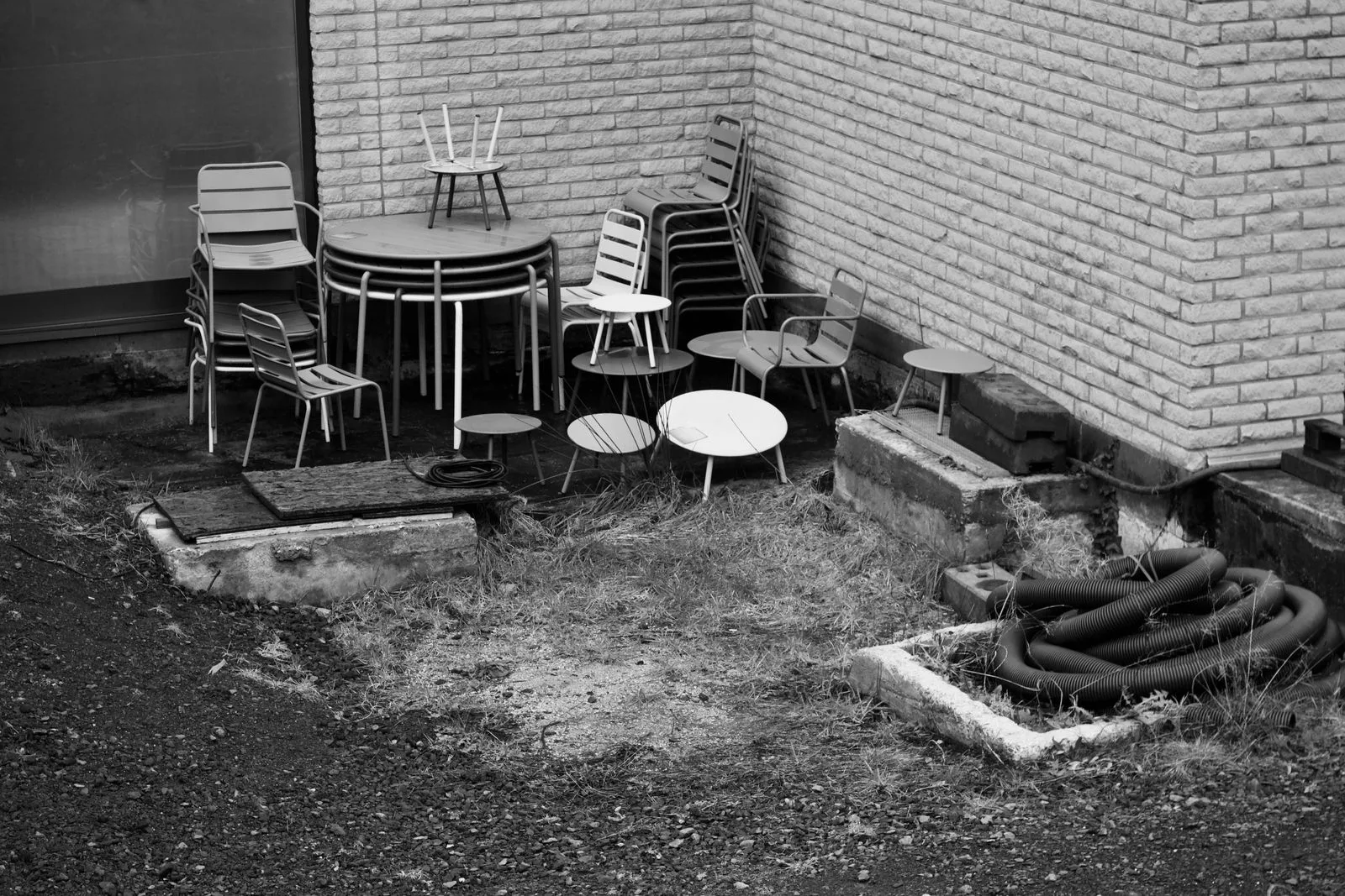 Chairs and tables stored outside beside brick walls and changes in ground level